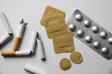 Photo of Nicotine patches, pills and broken cigarettes on white background, flat lay