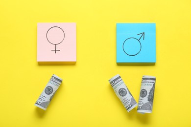 Gender pay gap. Paper notes with symbols and dollar banknotes on yellow background, flat lay