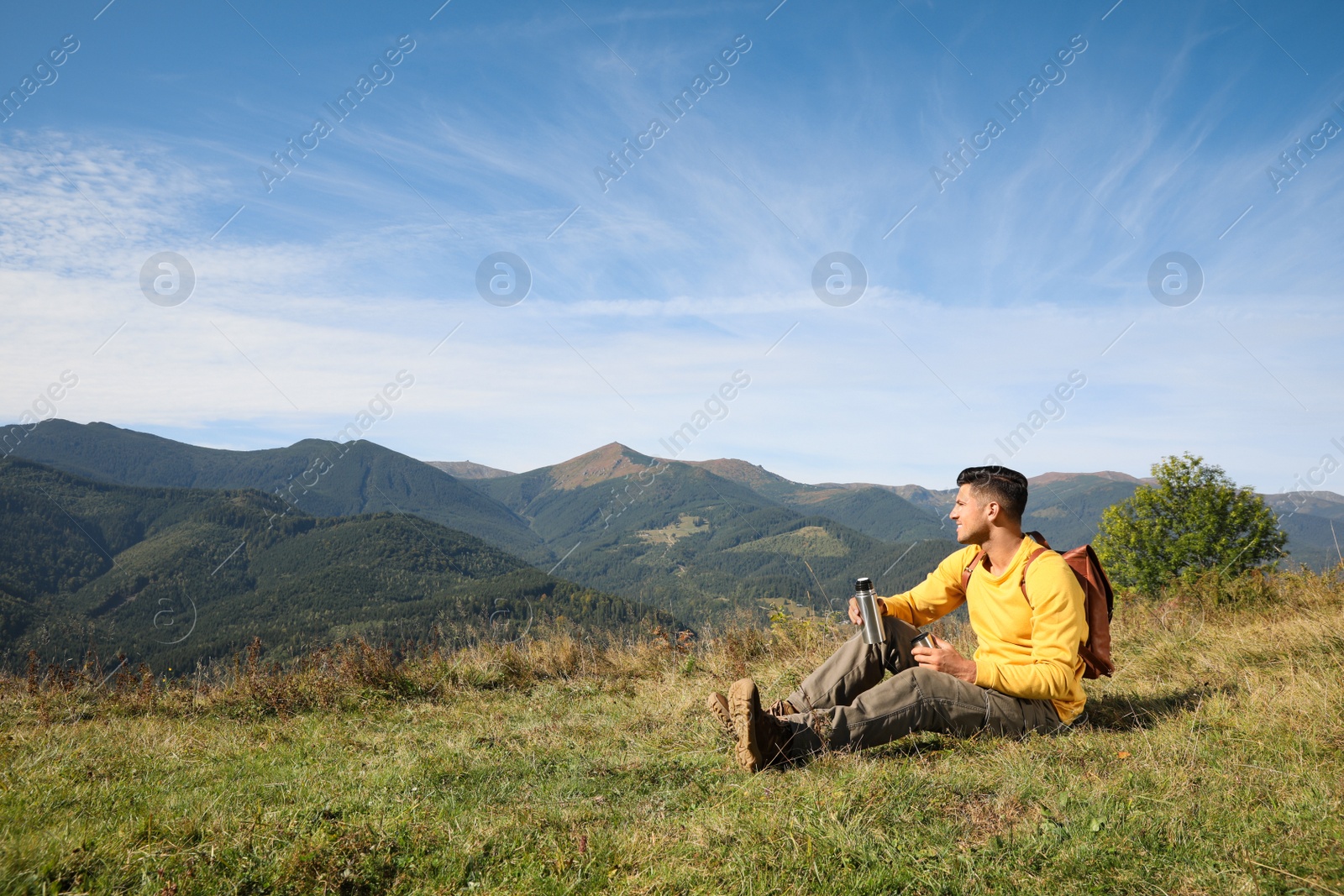 Photo of Tourist with thermos and backpack enjoying beautiful mountain landscape