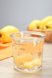 Photo of Delicious quince drink in glass and fresh fruits on wooden table, closeup