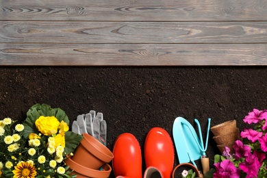 Flat lay composition with gardening equipment and flowers on soil, space for text