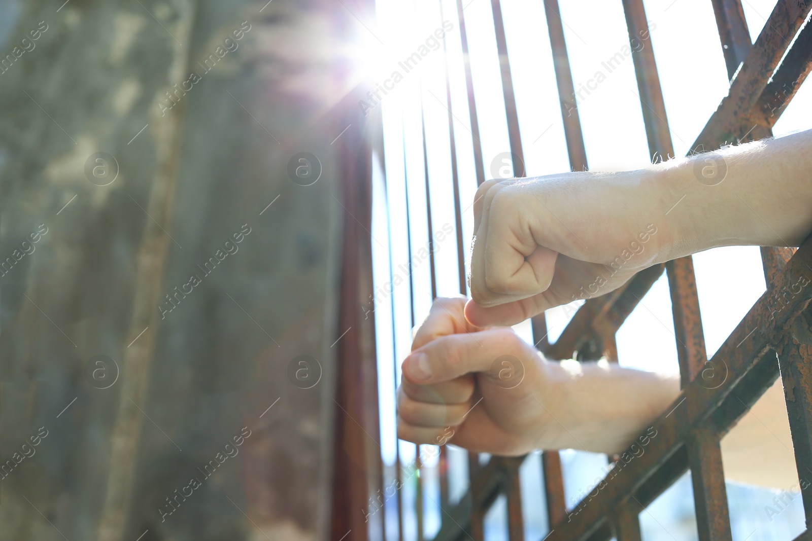Photo of Man detained in jail outdoors, space for text. Criminal law