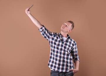 Handsome man taking selfie on color background