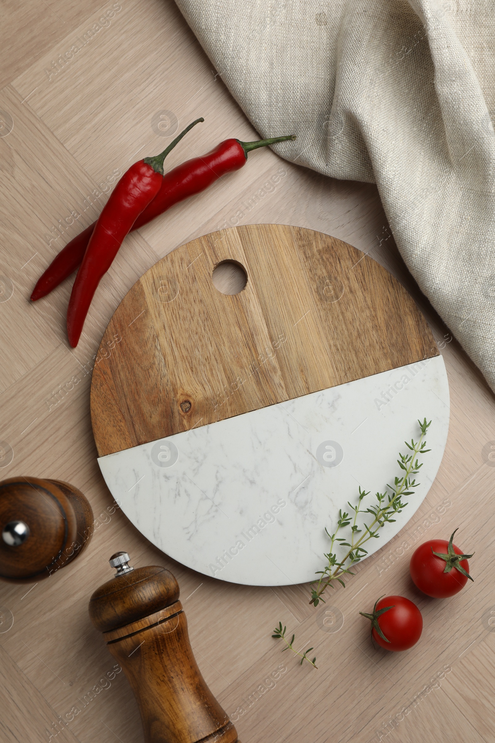 Photo of Cutting board and different spices on wooden table, flat lay