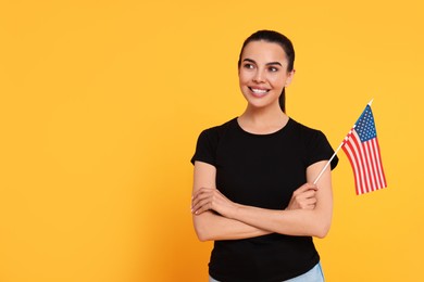 Photo of 4th of July - Independence Day of USA. Happy woman with American flag on yellow background, space for text