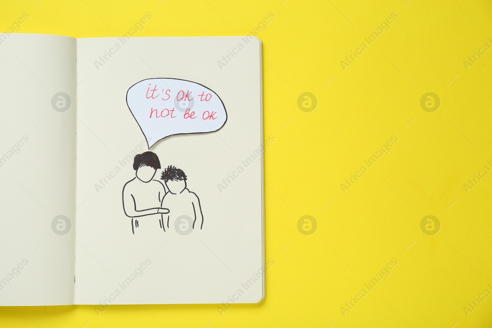 Photo of Card with phrase It`s Ok to Not Be Ok, drawing of mother and her son in notebook on yellow background, top view. Space for text
