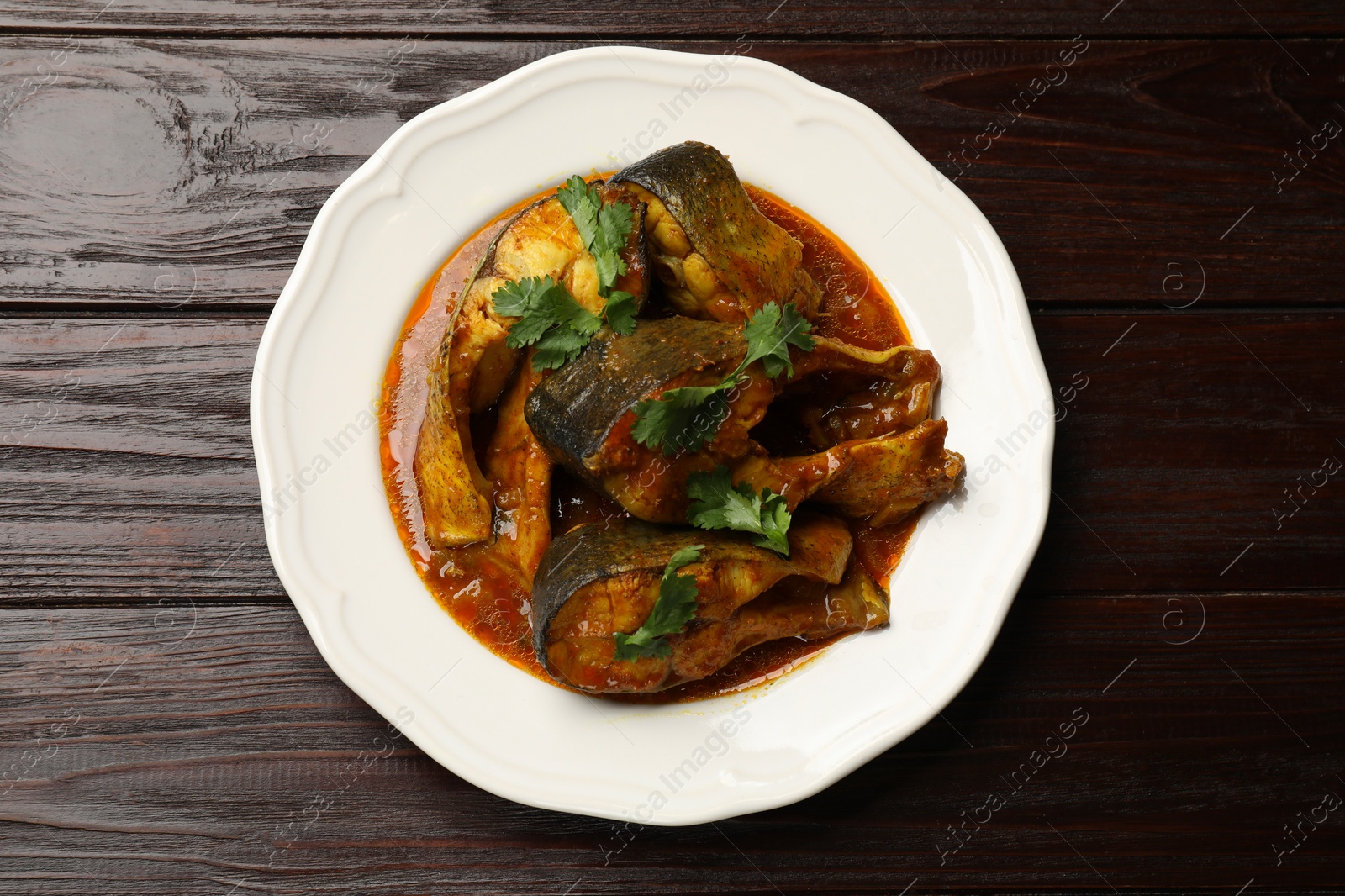 Photo of Tasty fish curry on wooden table, top view. Indian cuisine