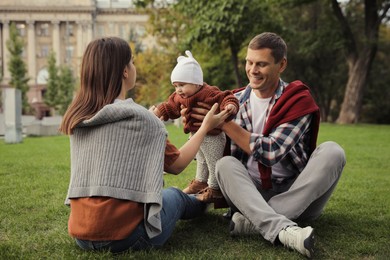 Photo of Happy parents with their adorable baby on green grass in park