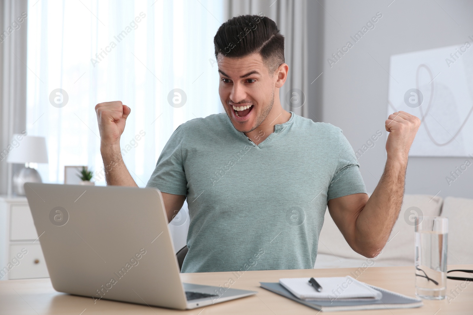 Photo of Emotional man participating in online auction using laptop at home