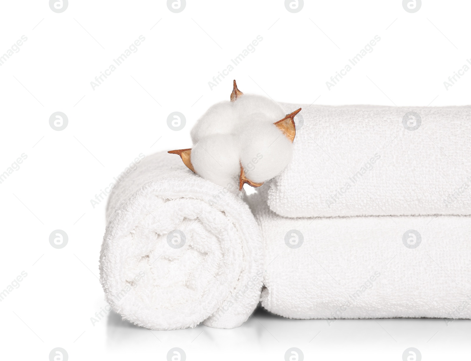 Photo of Soft terry towels with cotton flowers on white background