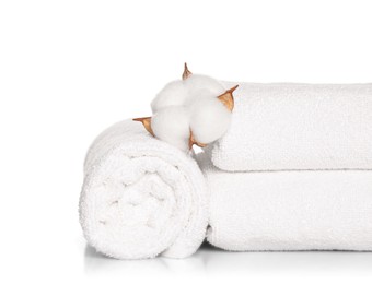Photo of Soft terry towels with cotton flowers on white background
