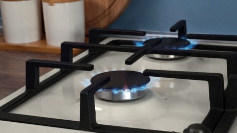 Photo of White gas cooktop with turned on burners in kitchen