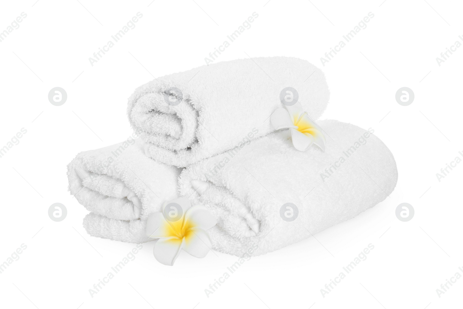 Photo of Rolled terry towels and plumeria flowers isolated on white