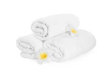 Photo of Rolled terry towels and plumeria flowers isolated on white