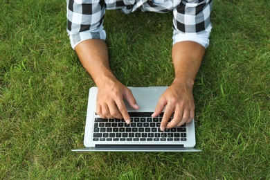 Photo of Young man working on laptop outdoors, closeup