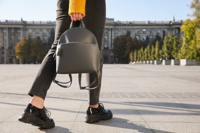 Photo of Woman with stylish black backpack on city street, closeup. Space for text