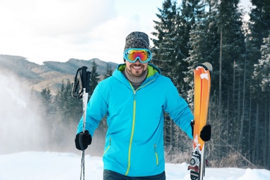 Man with ski equipment spending winter vacation in mountains