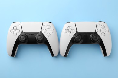 Wireless game controllers on light blue background, flat lay