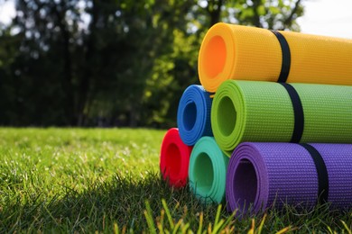 Bright exercise mats on fresh green grass outdoors, space for text