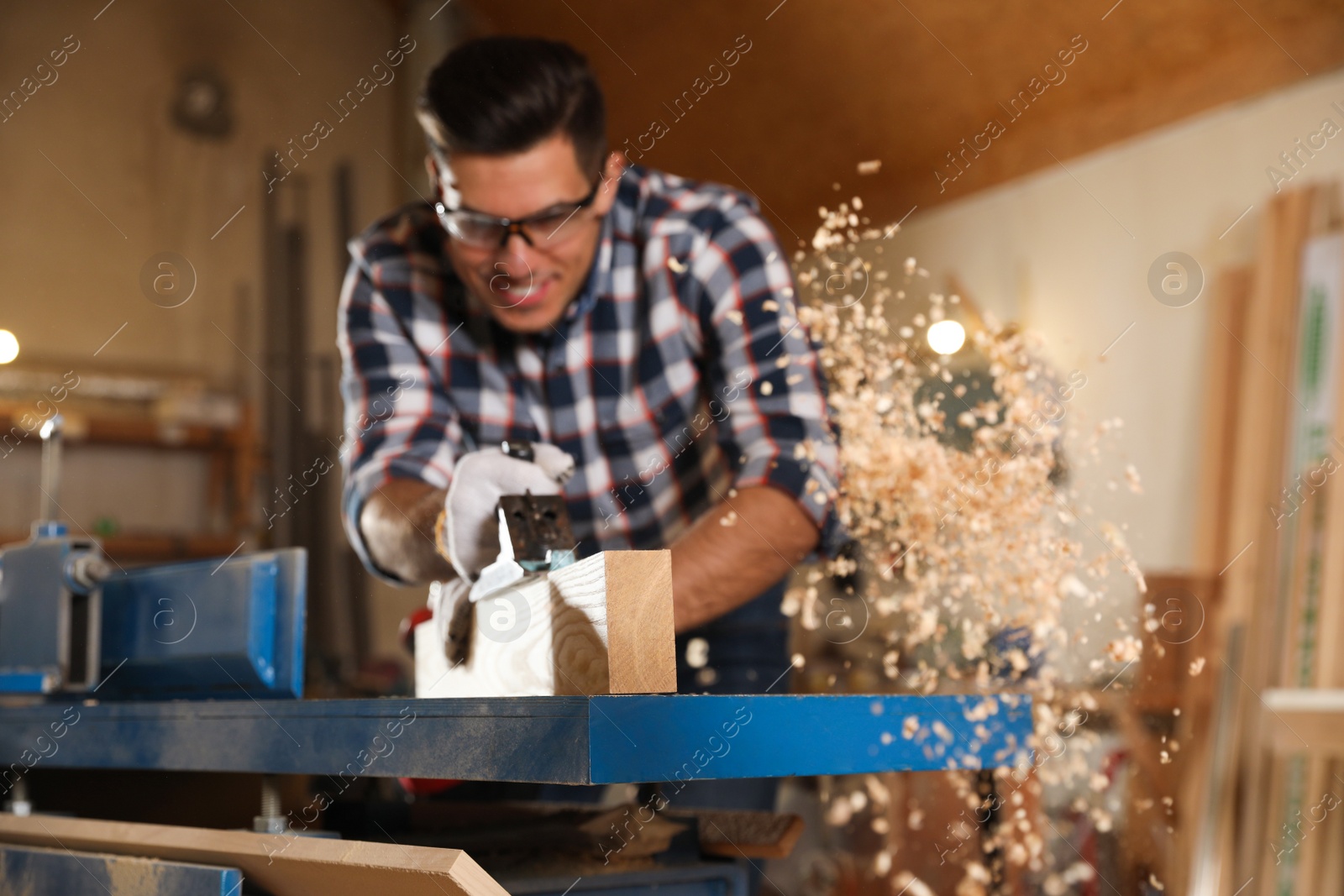 Photo of Professional carpenter grinding wooden board with jack plane in workshop, focus on plank