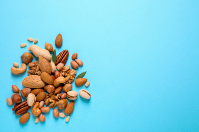 Photo of Different delicious nuts on light blue background, flat lay. Space for text