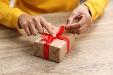 Photo of Man opening Christmas gift at wooden table, closeup