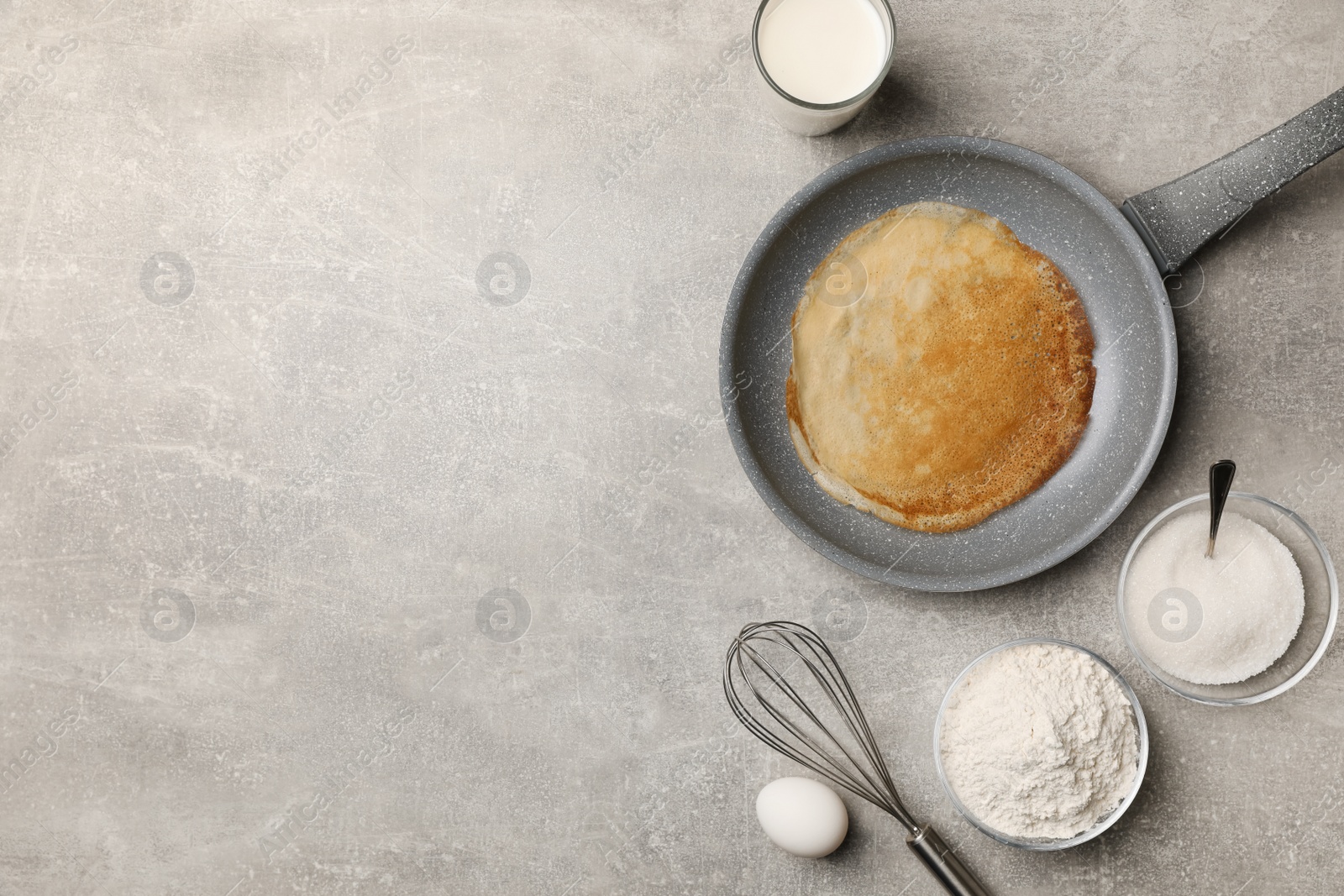 Photo of Frying pan with delicious crepe and ingredients on grey table, flat lay. Space for text