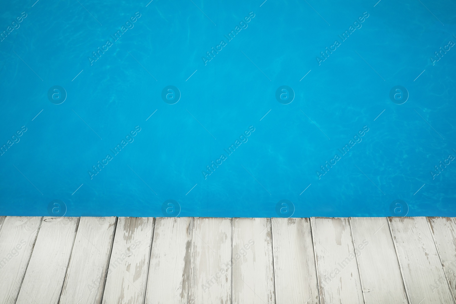 Photo of Wooden deck near swimming pool outdoors on sunny day. Space for text