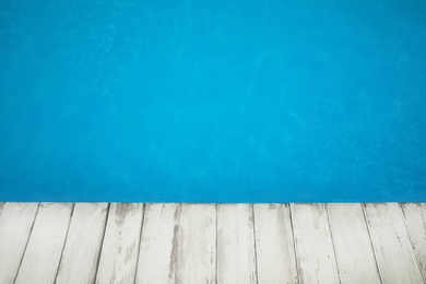 Wooden deck near swimming pool outdoors on sunny day. Space for text