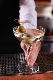 Photo of Bartender with fresh Martini cocktail at bar counter, closeup