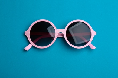 Photo of Stylish sunglasses on blue background, top view. Fashionable accessory