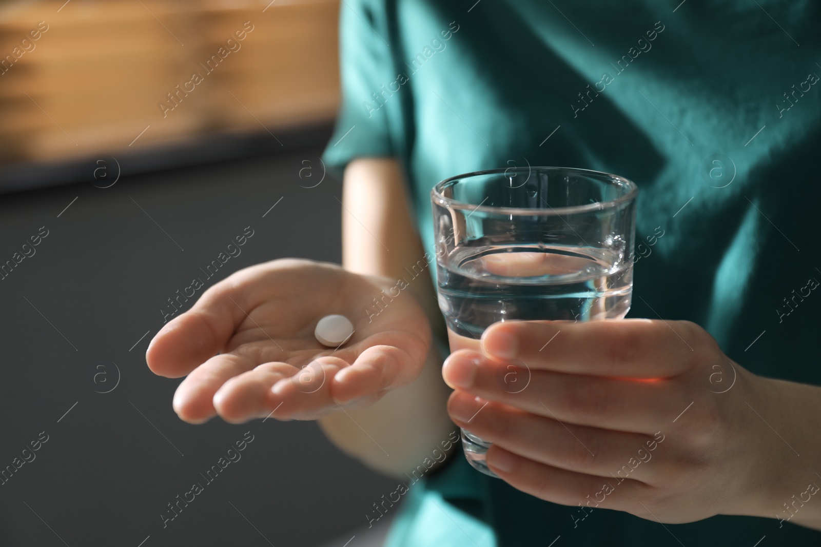 Photo of Young woman with abortion pill and glass of water indoors, closeup