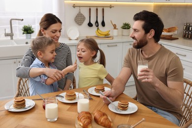 Happy family having fun during breakfast at table in kitchen