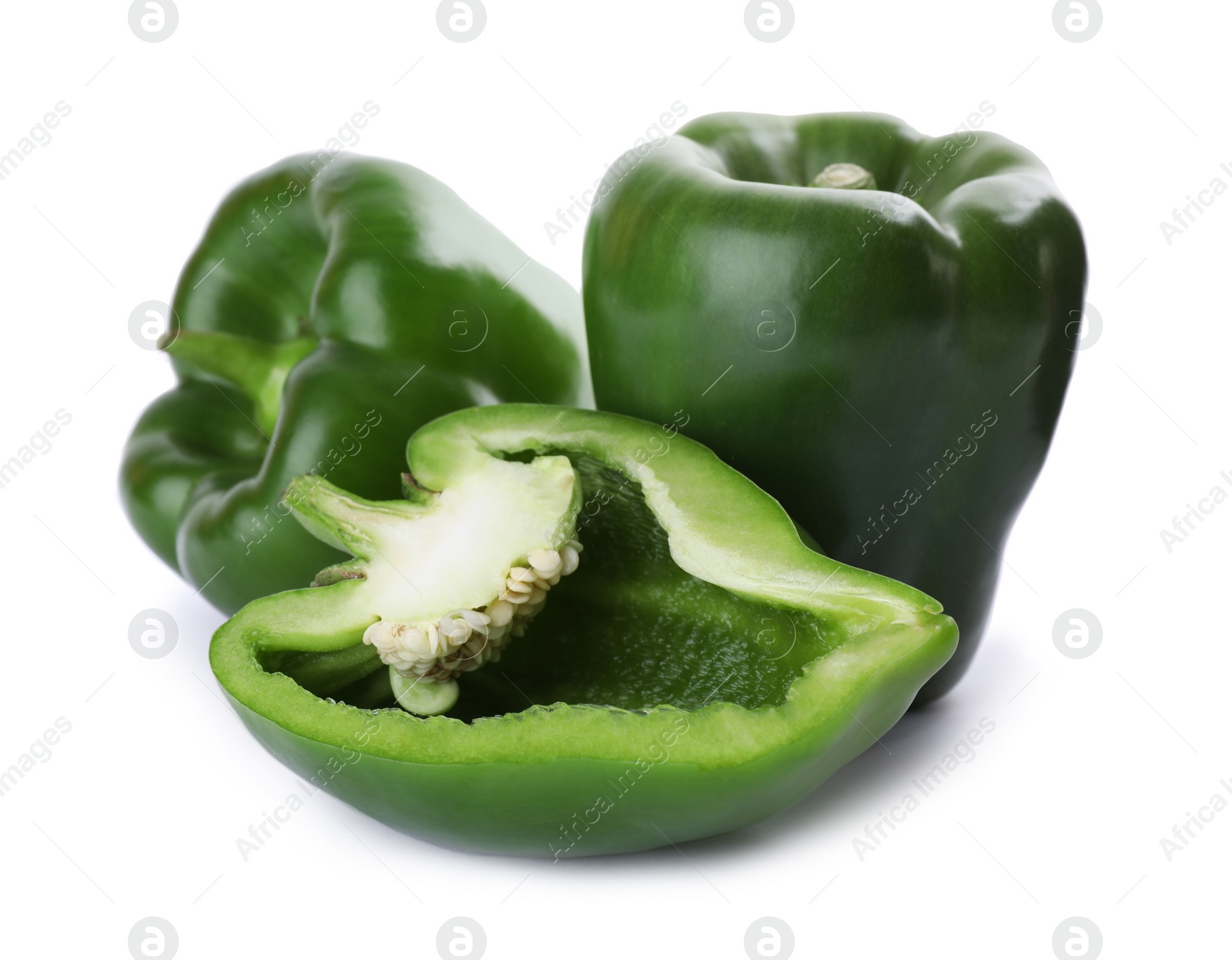 Photo of Whole and cut green bell peppers isolated on white