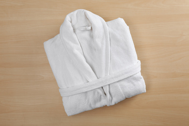 Photo of Clean folded bathrobe on wooden background, top view