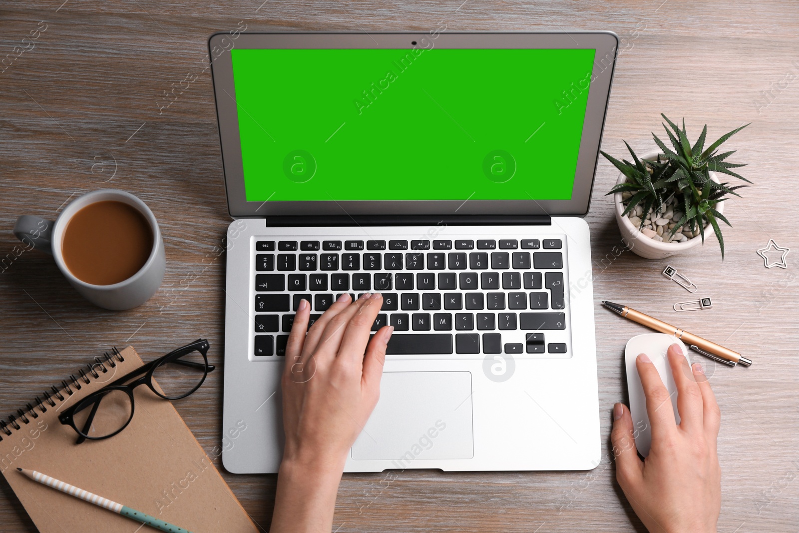 Image of Woman using laptop at wooden desk, top view. Device display with chroma key