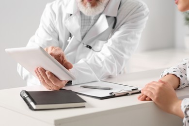 Photo of Patient having appointment with senior doctor at table in clinic, closeup