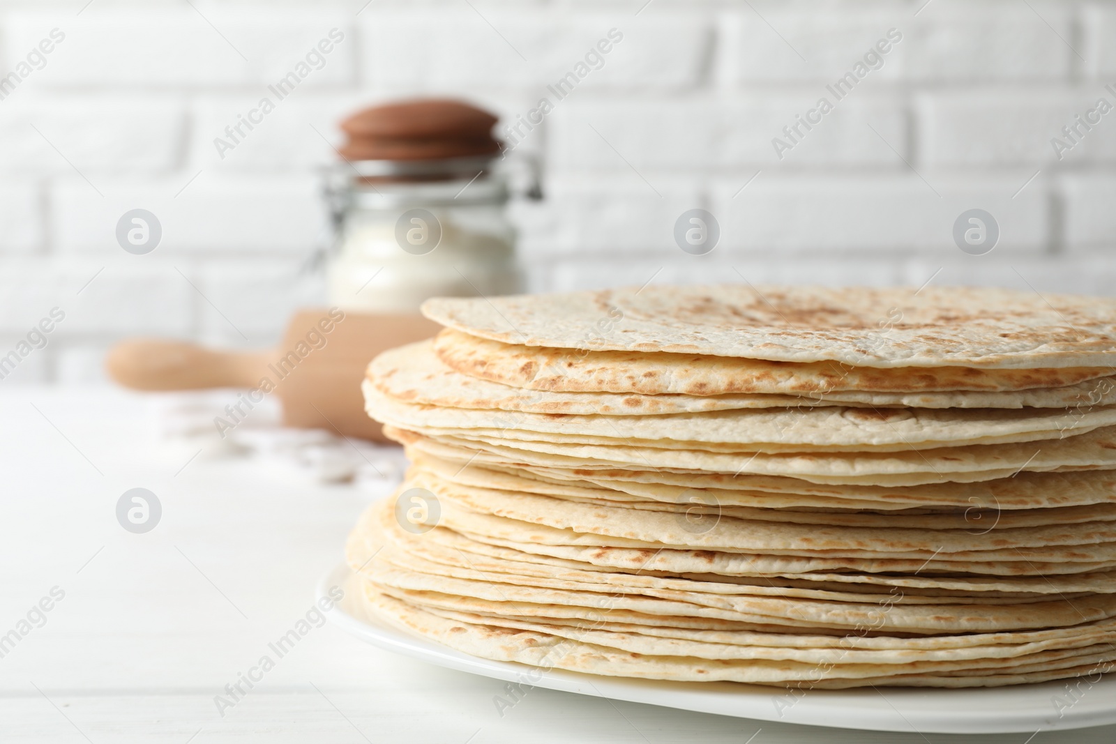 Photo of Stack of tasty homemade tortillas on white table, space for text