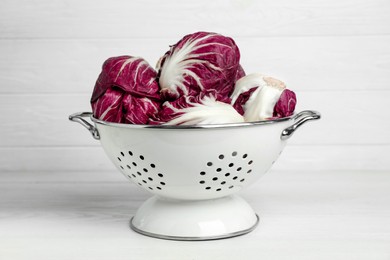 Fresh ripe radicchios in colander on white wooden table