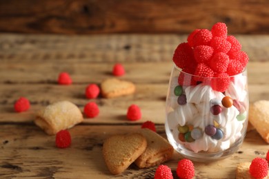 Photo of Delicious candies in glass and cookies on wooden table, closeup. Space for text
