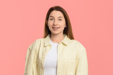 Portrait of smiling woman with dental braces on pink background