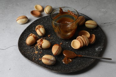Delicious walnut shaped cookies with condensed milk on grey table, closeup