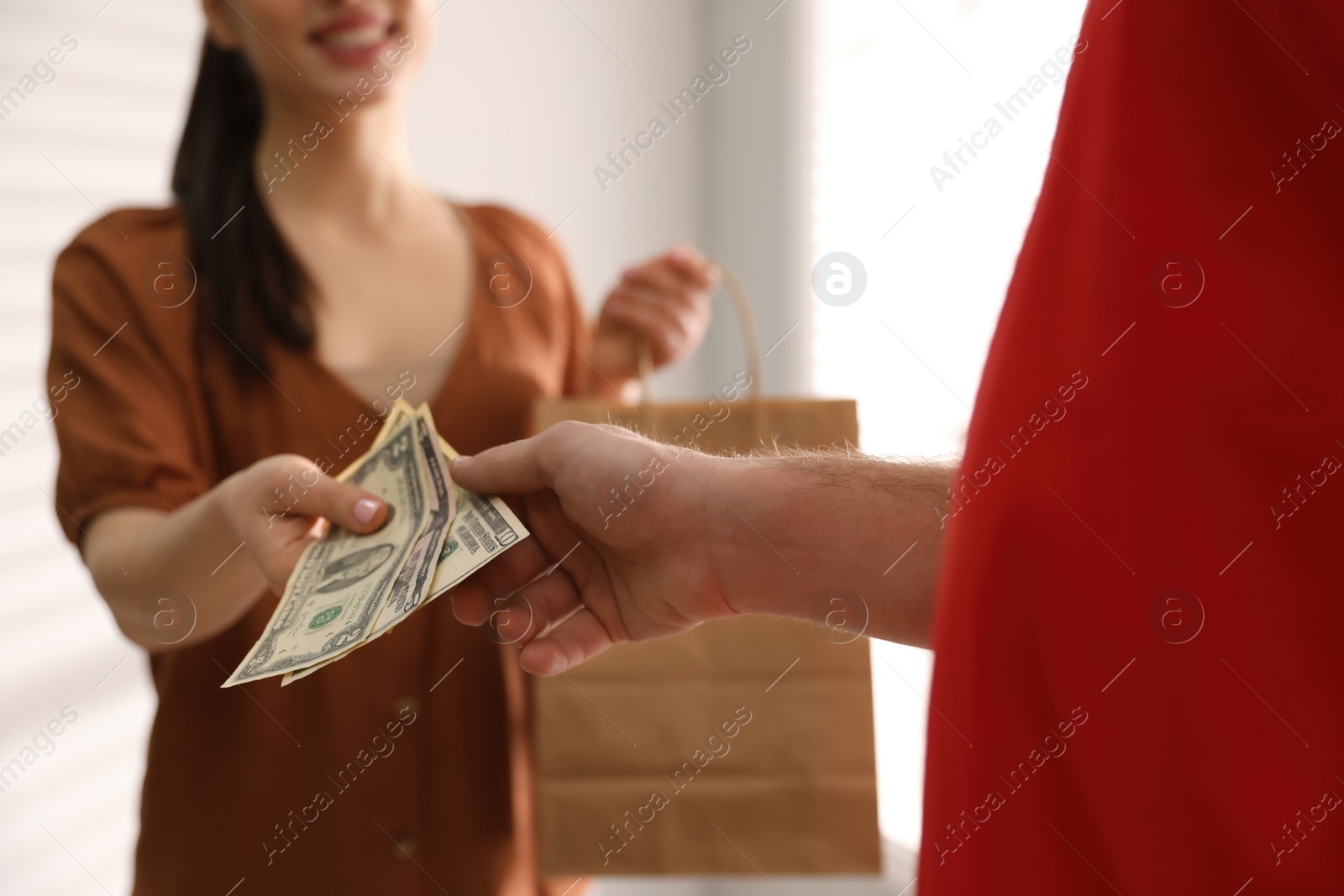 Photo of Woman giving tips to deliveryman indoors, closeup