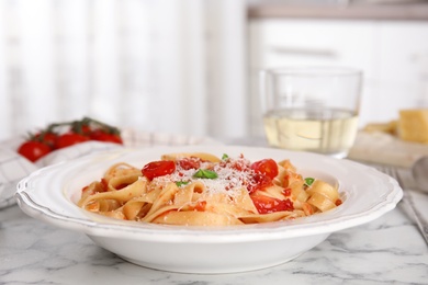 Photo of Tasty pasta with tomatoes, cheese and basil on white marble table