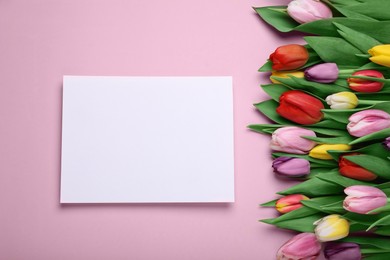 Photo of Beautiful tulips and blank card on pale pink background, flat lay