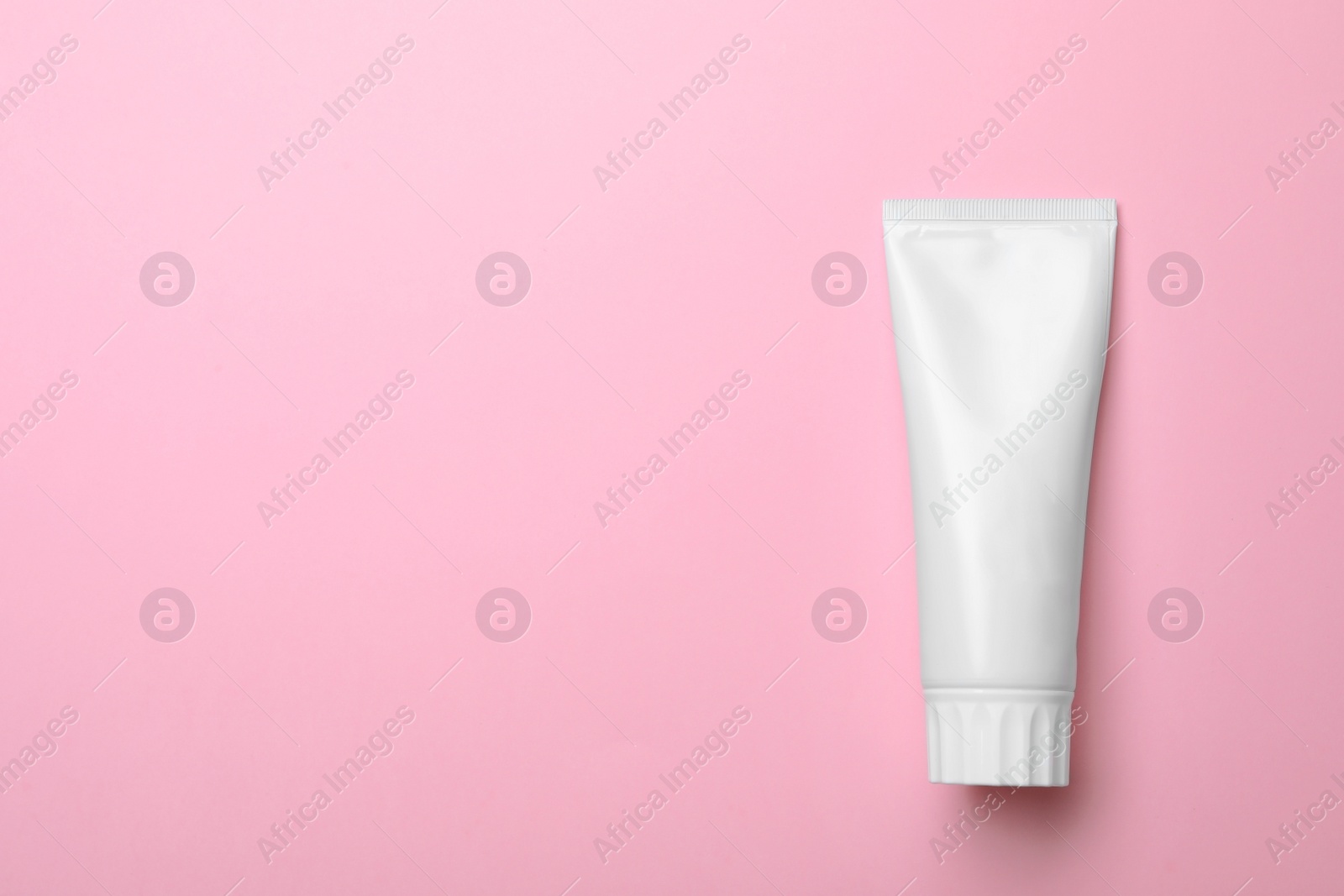 Photo of Blank tube of toothpaste on color background, top view with space for text