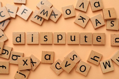 Photo of Squares with word Dispute on pale orange background, flat lay