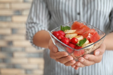 Photo of Woman holding bowl with delicious oatmeal and fruits, closeup. Healthy diet