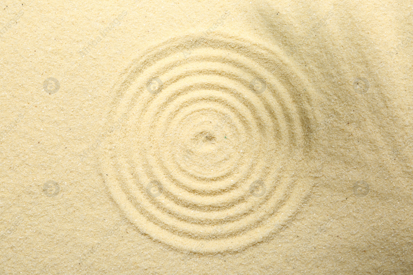 Photo of Zen rock garden. Circle pattern on beige sand, top view