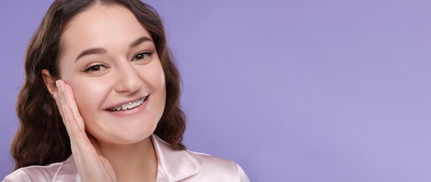 Smiling woman with braces on violet background. Banner design with space for text